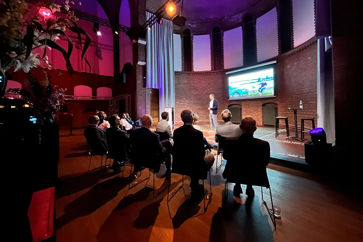Wiebe Wakker op het podium in een theater, terwijl hij een presentatie geeft.