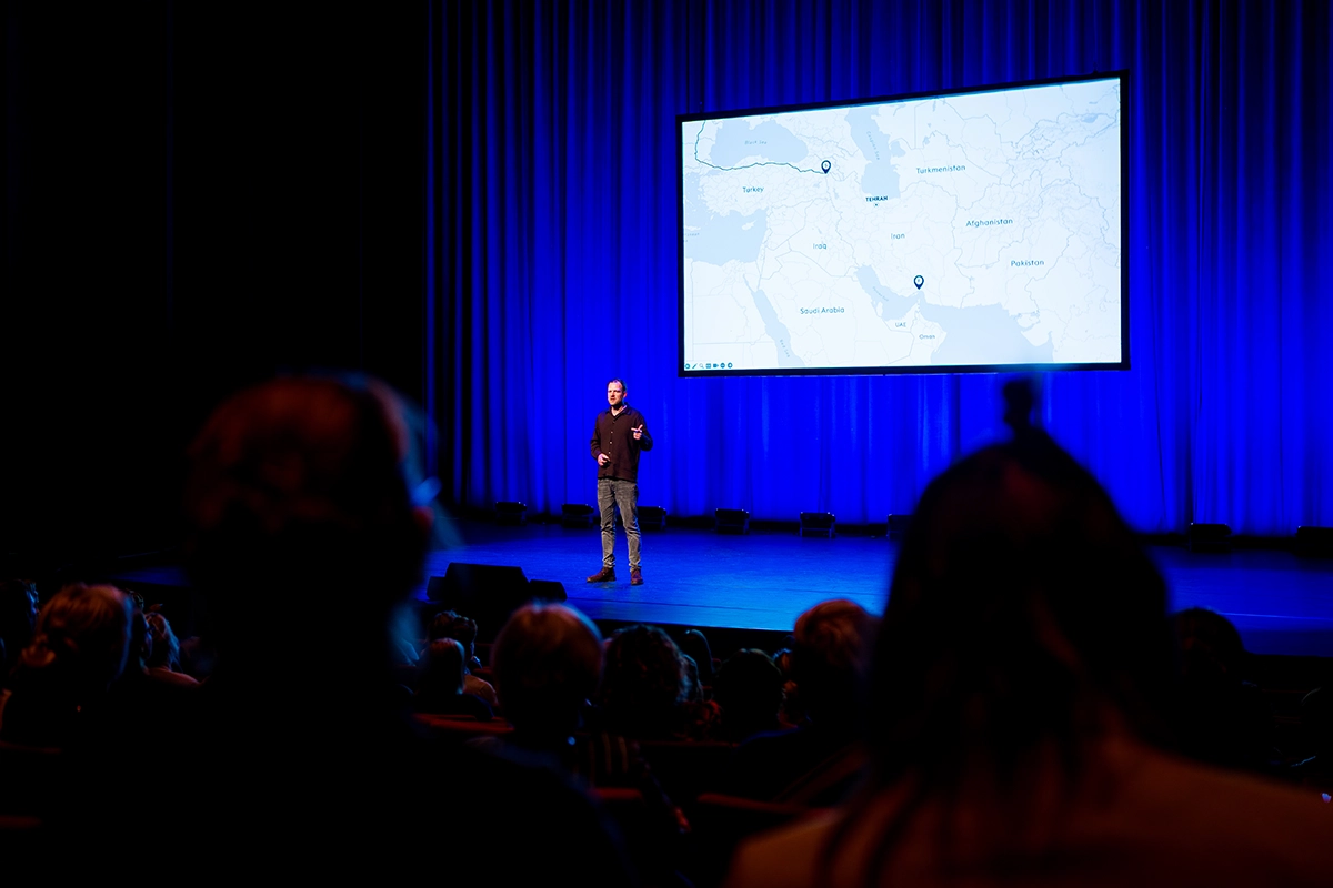 Wiebe Wakker op het podium in een theater, terwijl hij een presentatie geeft.