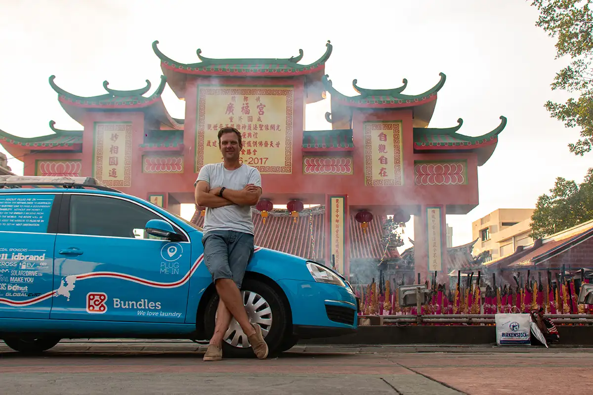 Wiebe Wakker zit op de motorkap van zijn auto voor een tempel in Penang, Maleisië.